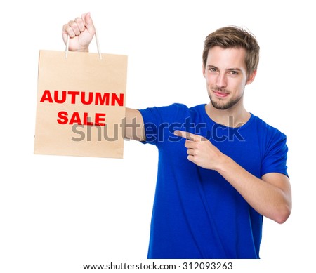 Man finger point to the shopping bag and showing phrase autumn sale