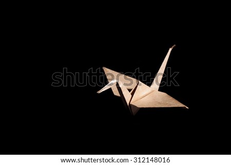 Origami bird made from brown recycle paper isolated on black background