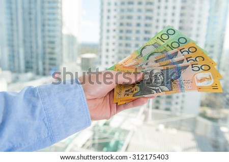 Human hand with Australian money with business building 