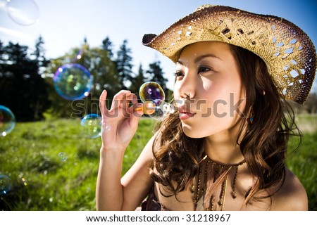 A beautiful asian girl having fun playing bubbles outdoor during summer