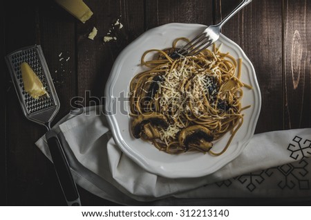 Whole grain spaghetti with mushrooms and parmesan cheese, dark picture, focus on detail and darkness