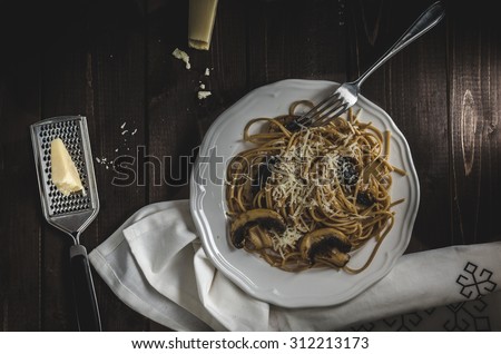 Whole grain spaghetti with mushrooms and parmesan cheese, dark picture, focus on detail and darkness