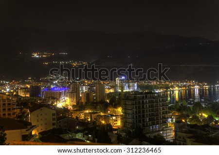 Beautiful HDR night photo of a popular vacation destination, the Budva city, and coast with lights reflecting of the waterscape and large mountainscape in the background, Montenegro