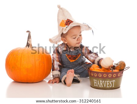Adorable baby boy dressed as a scarecrow and playing with gourds and pumpkins.  Isolated on white with room for your text.