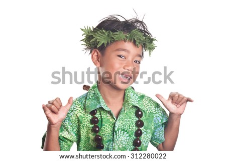 Young boy spreads the spirit of Aloha with a shaka hand gesture while wearing a green head lei and a brown kukui shell necklace
