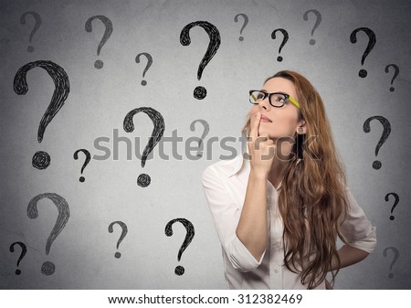 Thinking business woman with glasses looking up on many questions mark isolated on gray wall background Royalty-Free Stock Photo #312382469