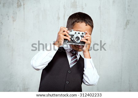 Small black boy in suit makes a photo of you