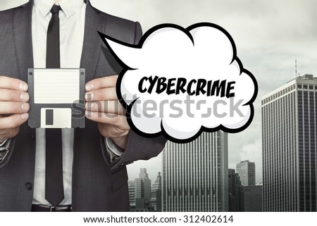 Cybercrime text on speech bubble with businessman holding diskette on cityscape background