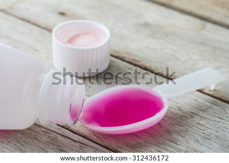 liquid medicine in plastic spoon on wooden table.