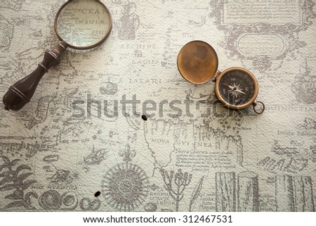 Magnifier with lantern with compass on the old map