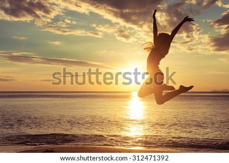 Happy teen girl  jumping on the beach at the sunset time