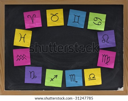 blackboard  blank copy space a surrounded by twelve zodiac signs sketched with black pen on colorful crumpled sticky notes