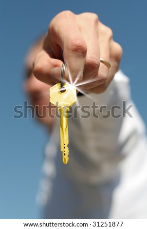 hand holds a gold key (key in focus)