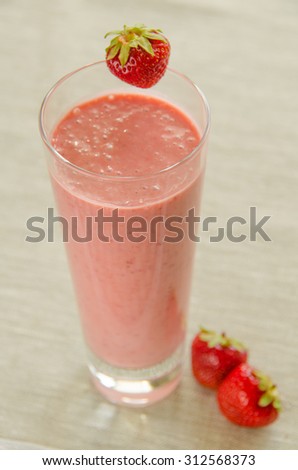 strawberry smoothie with a plate of strawberries on the table