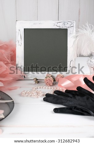 Old photo frame and women's retro accessories including velvet gloves and pearl necklace on wooden  table 
