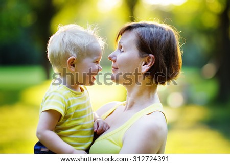 Beautiful middle aged woman and her adorable little grandson at sunny park
