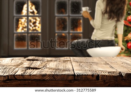 blurred background of xmas tree and window with xmas tree on street with shabby wooden table space 