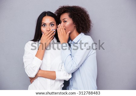 Portrait of a two girls gossip on gray background Royalty-Free Stock Photo #312788483