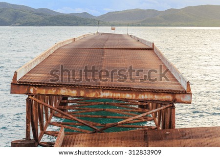 The old and rusty steel bridge broken over the sea