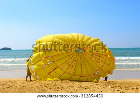 The yellow parachute on the beach on sunny day afternoon, selective focus on yellow parachute