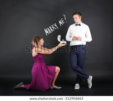 Romantic woman proposing to a man on black background Royalty-Free Stock Photo #312906863