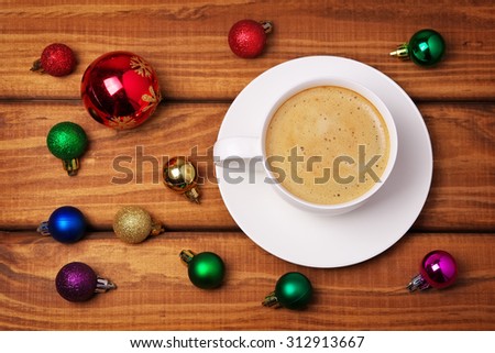 Cup of coffee and different christmas bubbles on wooden background.