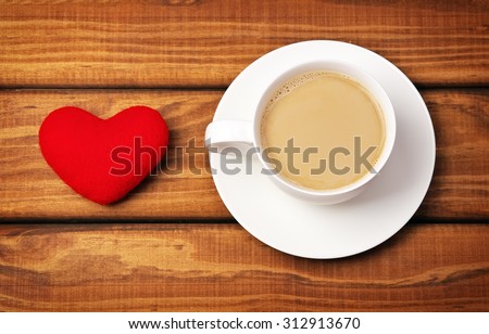 Cup of coffee and heart on wooden background.