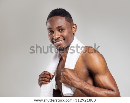 Positive african american muscular man after sports training with white towel