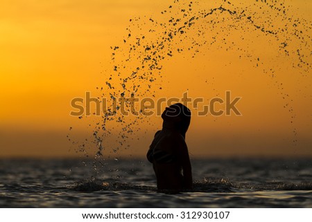 girl throwing water with her hair in the ocean during sunset