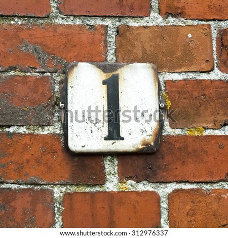 enameled house number one on a red brick wall.