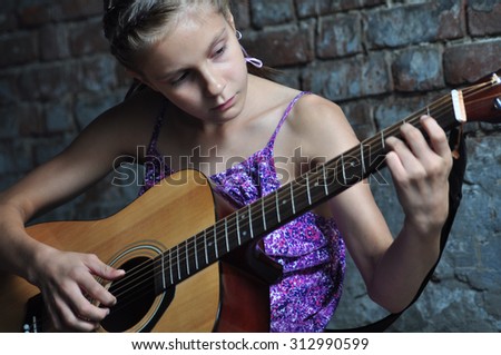Child playing acoustic guitar in the street