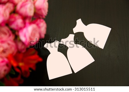 Three cards in the form of pink dress on a dark wooden background with roses