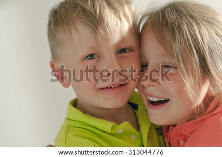 The closeup picture of the hugging siblings over light background