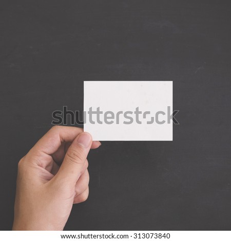 A portrait of Hand holding a blank white card. black background. Mock Up
