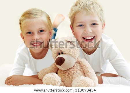 Two cute children playing with a teddy bear