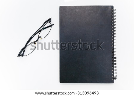 eyeglasses next to the black book