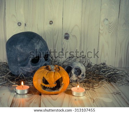 vintage tone image of rotten Halloween pumpkin with candle light and dry grass. Wooden background.