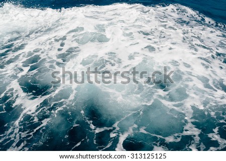 white foam on the surface of the blue sea water