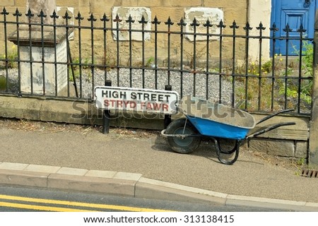 Welsh High Street sign - Stryd Fawr - with blue wheel barrow and iron railings. 