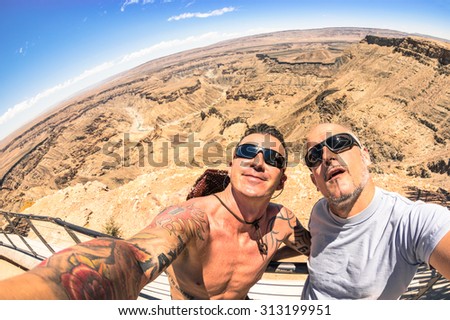 Adventurous best friends taking selfie at Fish River Canyon in Namibia - Adventure travel lifestyle enjoying happy fun moment - Trip together around the world beauties - Fisheye horizon distortion