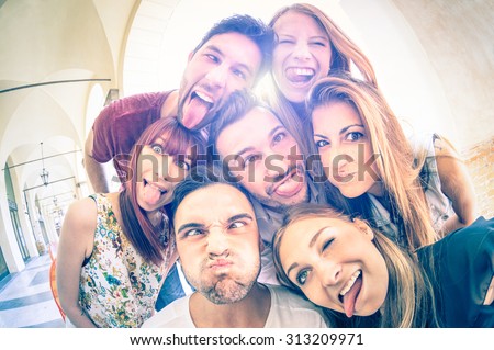 Best friends taking selfie outdoors with backlighting - Happy friendship concept with young people having fun together - Cold vintage filtered look with soft focus on faces due to sunshine halo flare Royalty-Free Stock Photo #313209971