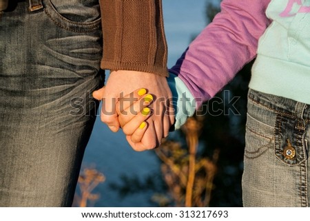 The mother holds the hand of his daughter in a summer day outdoors