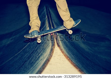 skateboarder performing a rail slide in the middle of the board in a skate park with a shallow depth of field with a toned retro instagram filter