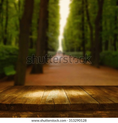 vintage wooden board table in front of dreamy autumn abstract forest landscape
