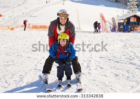 Beautiful young mom and her toddler boy, skiing in the mountains, winter time