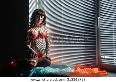 Young pregnant woman with bodyart on her belly studio shot