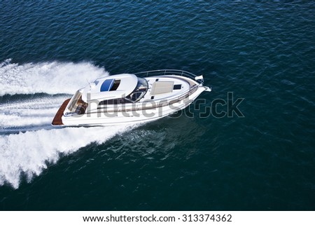 Aerial shot of a beautiful white motor boat with brown details sailing across the sea