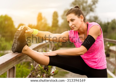 Attractive young runner woman doing stretching exercises. Royalty-Free Stock Photo #313396169