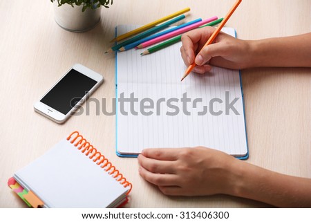 Woman write on notebook on workplace close up