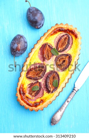 tart of pastry with plums on a blue background